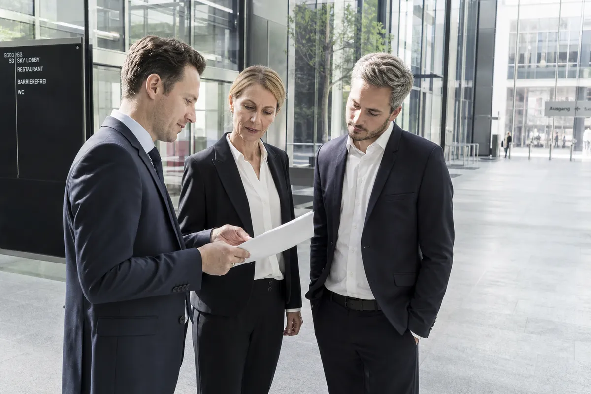 Kleine Gruppe mit Unterlagen in einem modernen Bürofoyer